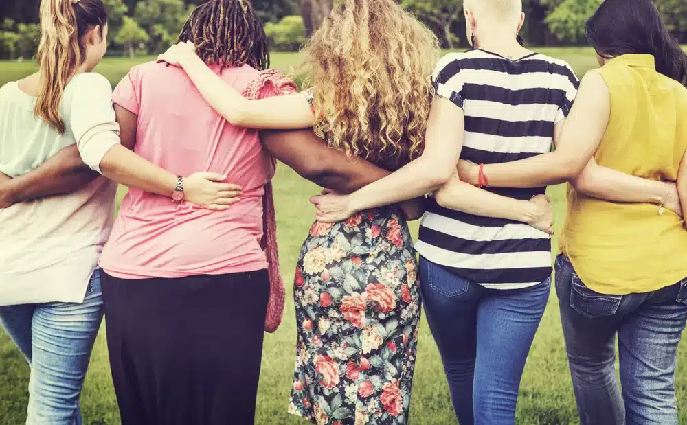 Five women holding arms from behind