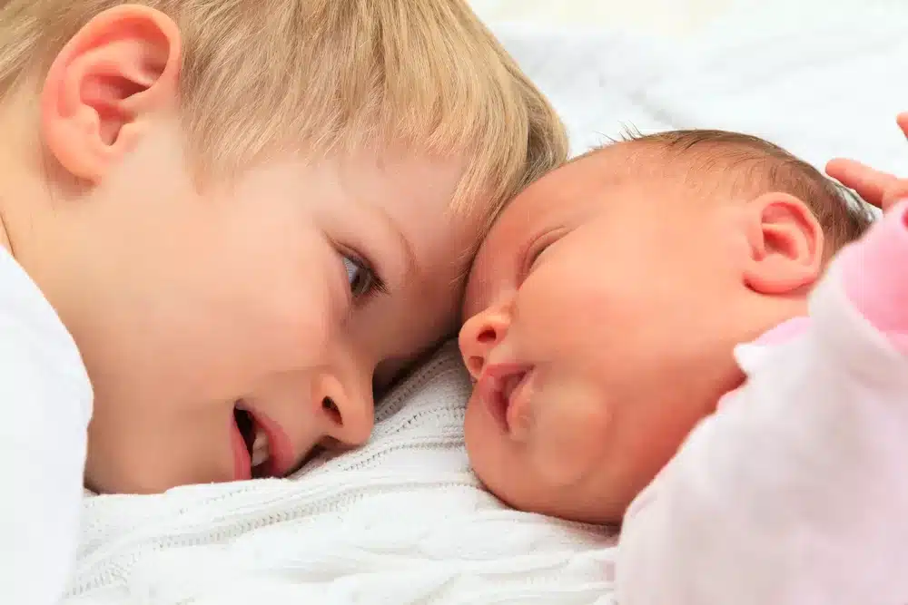 Child laying head-to-head with baby