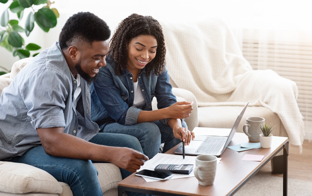 Couple reviewing numbers on a spreadsheet smiling