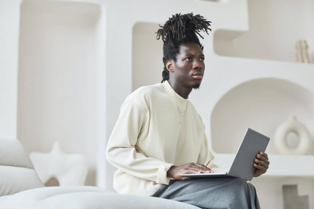 Man holding laptop looking quizzical